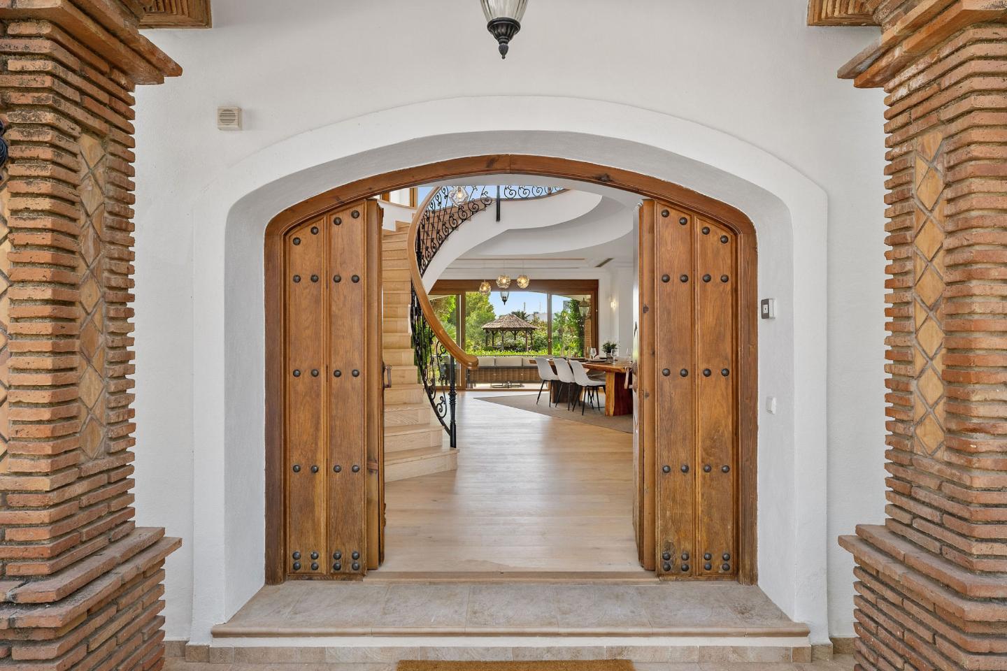 Inviting entrance to an authentic Andalusian villa with breathtaking sea views, featuring a grand doorway, rustic architectural details, and lush landscaping that creates a warm welcome while showcasing the villa's timeless charm and ocean vistas.