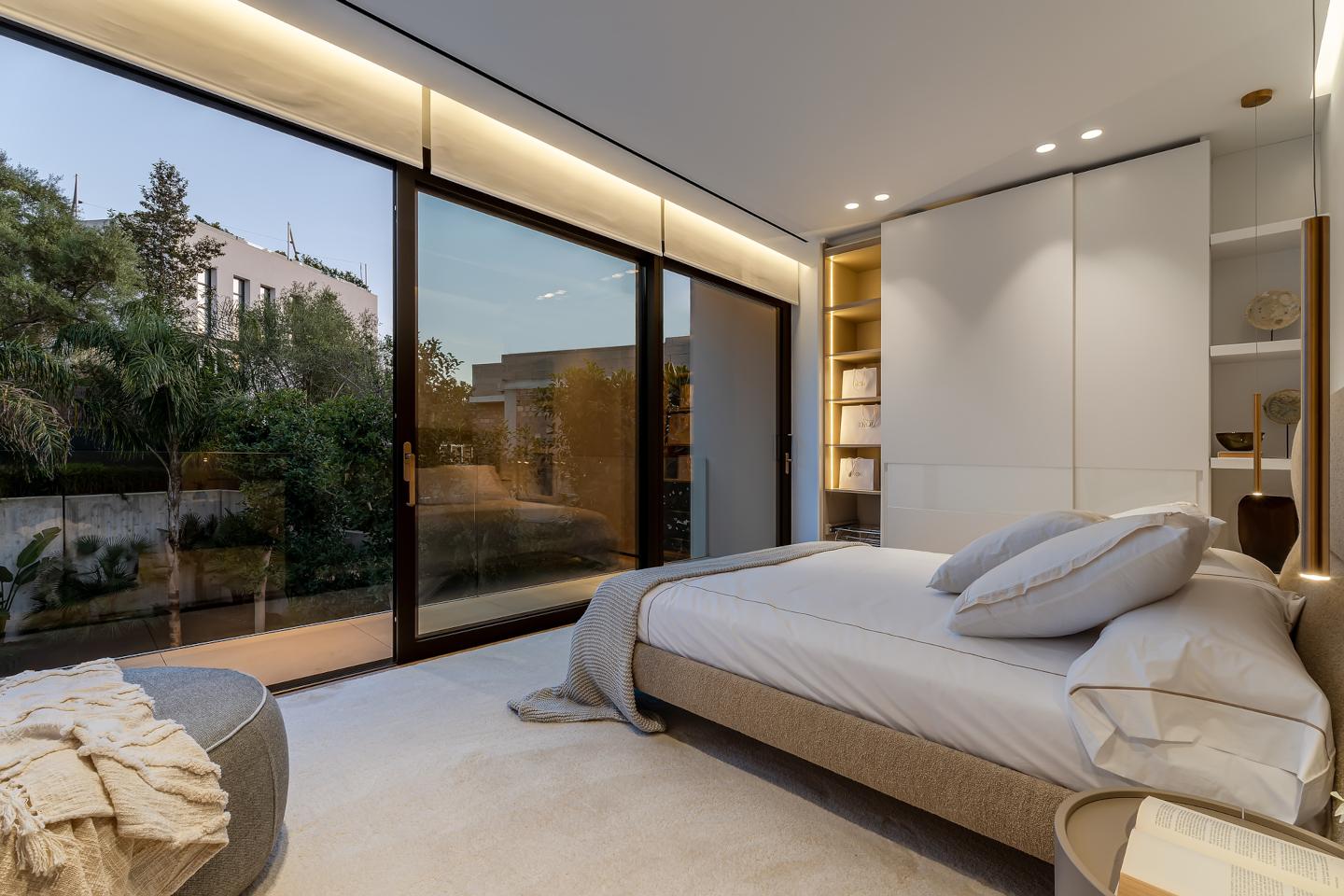 Luxurious bedroom in a contemporary beachside villa in Bendinat, Mallorca, featuring floor-to-ceiling windows with breathtaking sea views, elegant modern furnishings, and a serene, minimalist design for ultimate relaxation.