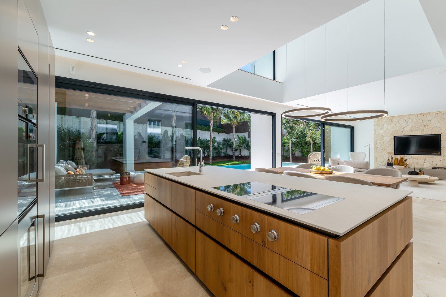 Elegant open-concept kitchen and dining area in a contemporary beachside villa in Bendinat, Mallorca, featuring sleek minimalist design, high-end appliances, and floor-to-ceiling windows that offer stunning sea views and seamless indoor-outdoor living.