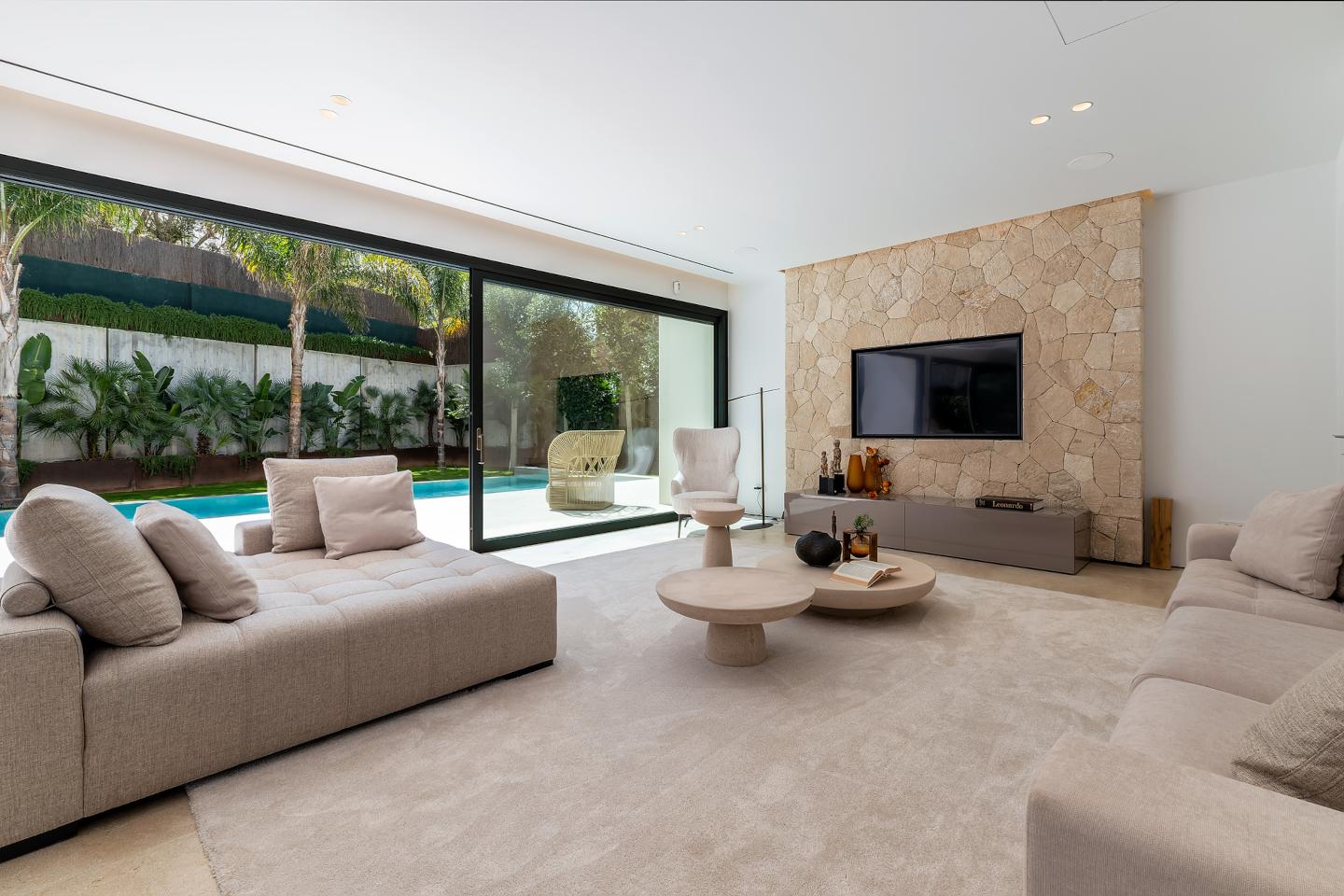 Sophisticated living room in a contemporary beachside villa in Bendinat, Mallorca, featuring sleek modern furnishings, floor-to-ceiling windows, and an open-concept design that seamlessly connects to the outdoor terrace with stunning sea views.