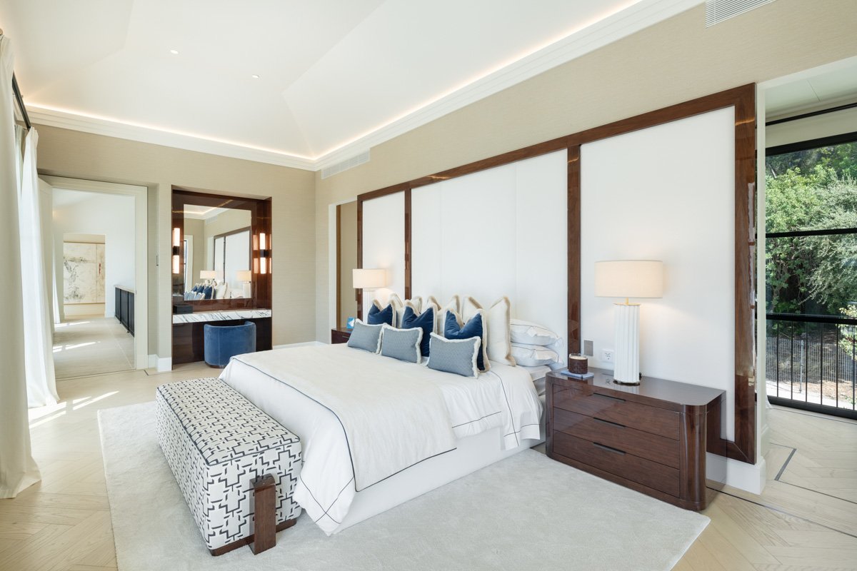 A luxurious bedroom with a contemporary design, featuring a king-size bed and large glass doors that open onto a spacious terrace. The room is flooded with natural light, offering stunning views of the surrounding landscape, while the terrace provides a serene outdoor space to relax and enjoy the beauty of the Golden Mile.