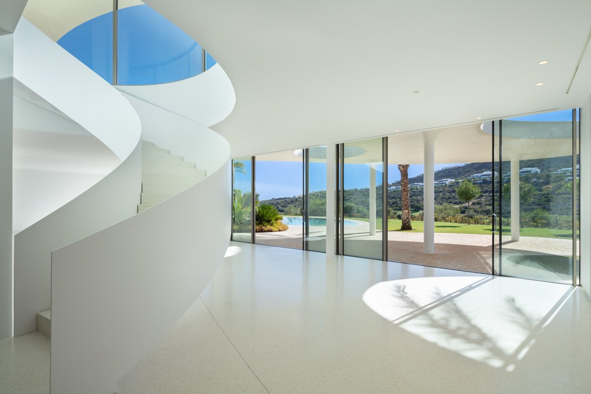 Impressive entrance to a futuristic villa in Finca Cortesín, Marbella, designed by Vicens Ramos, featuring bold architectural elements, sleek lines, and large glass doors that open into a luxurious and modern interior, setting the tone for the villa’s innovative design and refined elegance.