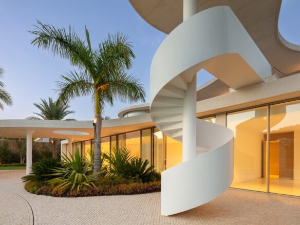 Striking facade of a futuristic villa in Finca Cortesín, Marbella, designed by Vicens Ramos, featuring innovative architecture with sleek lines, expansive glass panels, and bold geometric shapes, blending modern luxury with the villa’s natural surroundings to create a stunning visual impact.