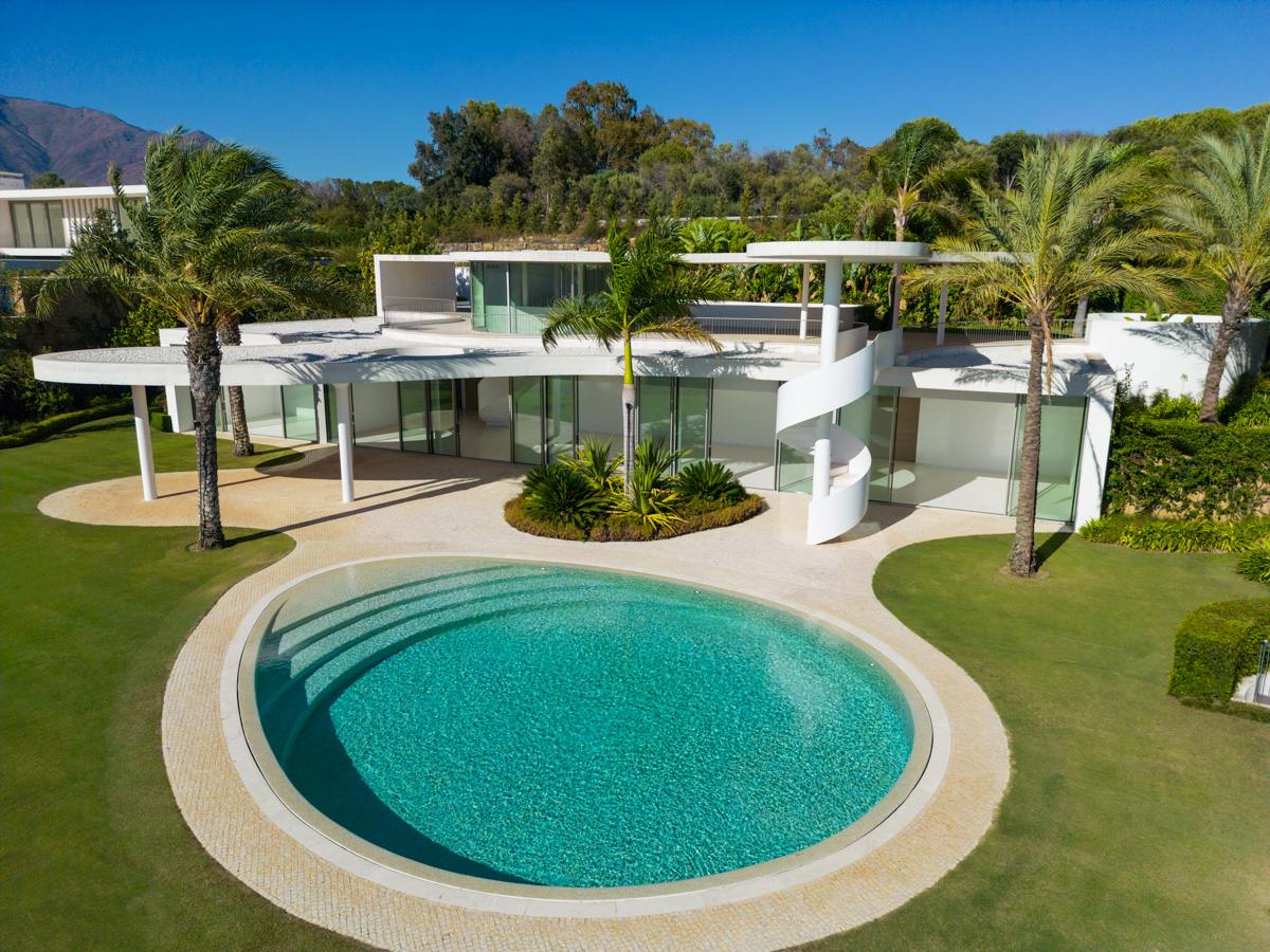 A striking infinity pool at a futuristic villa in Finca Cortesin, Marbella, with crystal-clear water that blends effortlessly with the horizon. The pool is surrounded by modern landscaping and sleek architecture, offering a serene and luxurious outdoor space with panoramic views of the surrounding natural beauty.