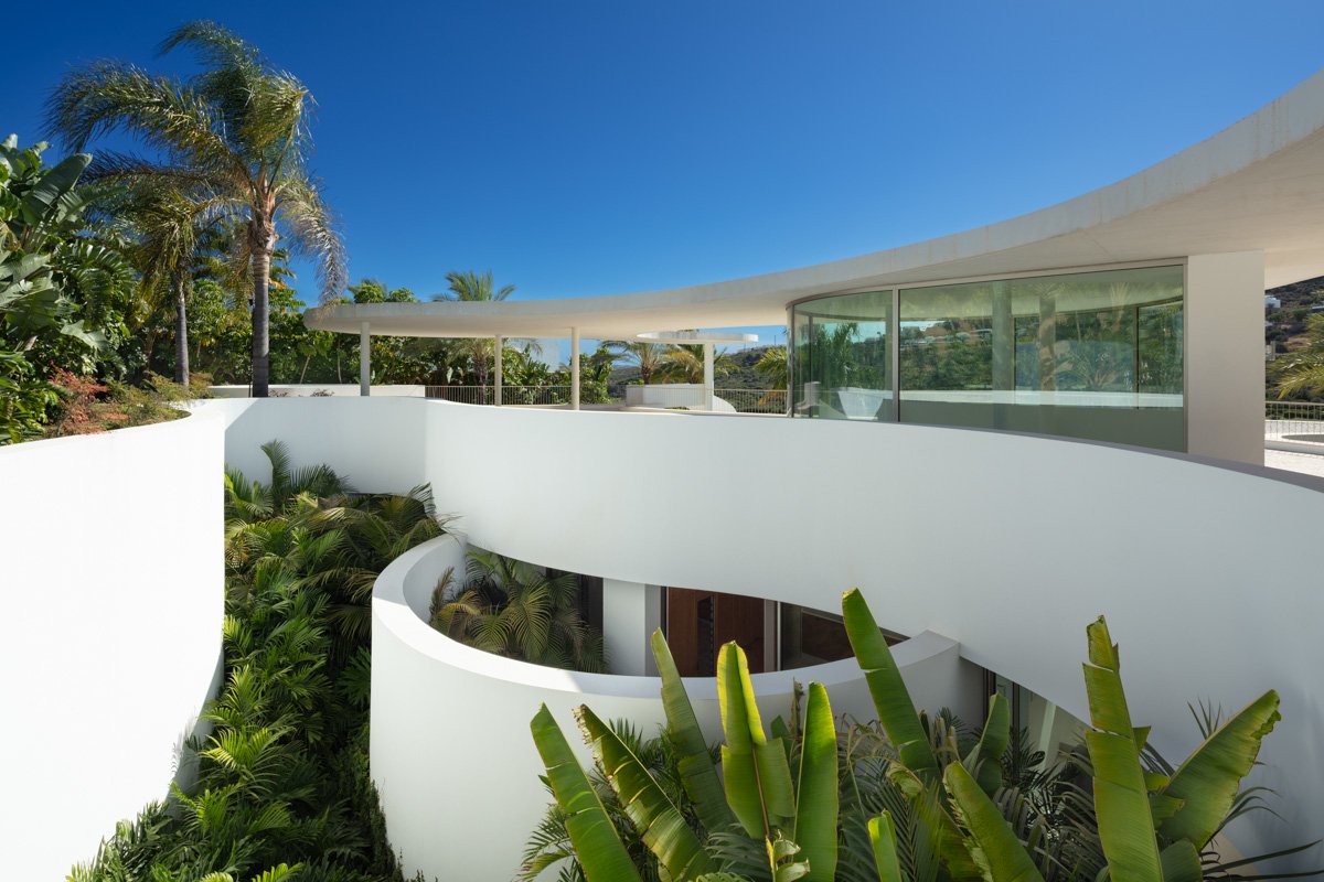 A modern villa terrace with sleek, minimalist design featuring spacious outdoor seating areas, glass railings, and lush greenery. The terrace offers stunning views of the surrounding landscape, creating a perfect space for relaxation and enjoying the luxurious ambiance of the futuristic villa.