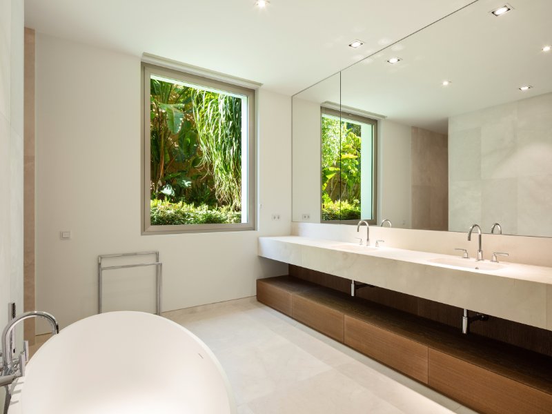 Elegant bathroom in a golfside luxury villa in Finca Cortesín, featuring sleek modern fixtures, a freestanding bathtub with views of the lush golf course, and luxurious finishes that create a serene, spa-like atmosphere for ultimate relaxation.