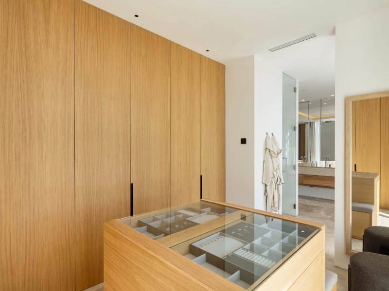 Spacious dressing room in a luxury villa with spectacular golf and mountain views, featuring custom cabinetry, elegant lighting, and ample storage space, creating a sophisticated and functional area for organizing clothing and accessories in a serene setting.