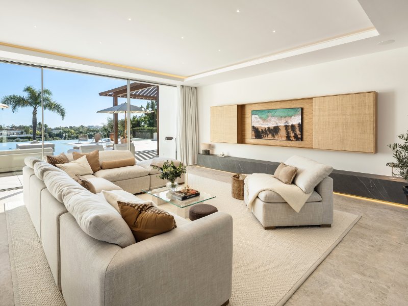 Sophisticated TV room in a luxury villa with stunning golf and mountain views, featuring plush seating, modern entertainment systems, and large windows that allow natural light to flood the space, offering a cozy yet elegant atmosphere for relaxation.