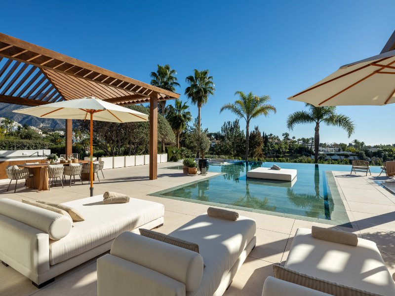 Stunning terrace and pool area in a luxury villa with breathtaking golf and mountain views, featuring an infinity pool, stylish outdoor seating, and a spacious layout perfect for relaxation and entertaining, blending modern design with natural beauty.