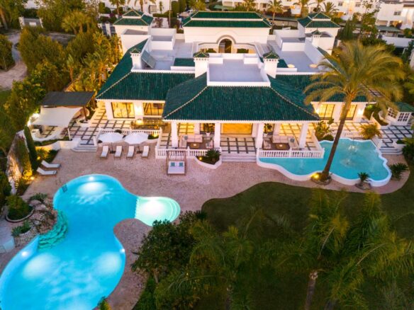 Impressive facade of a majestic Andalusian palace in Marbella, showcasing intricate architectural details, grand arches, and lush greenery, blending classic Andalusian style with modern luxury, reflecting the timeless beauty and elegance of the property.