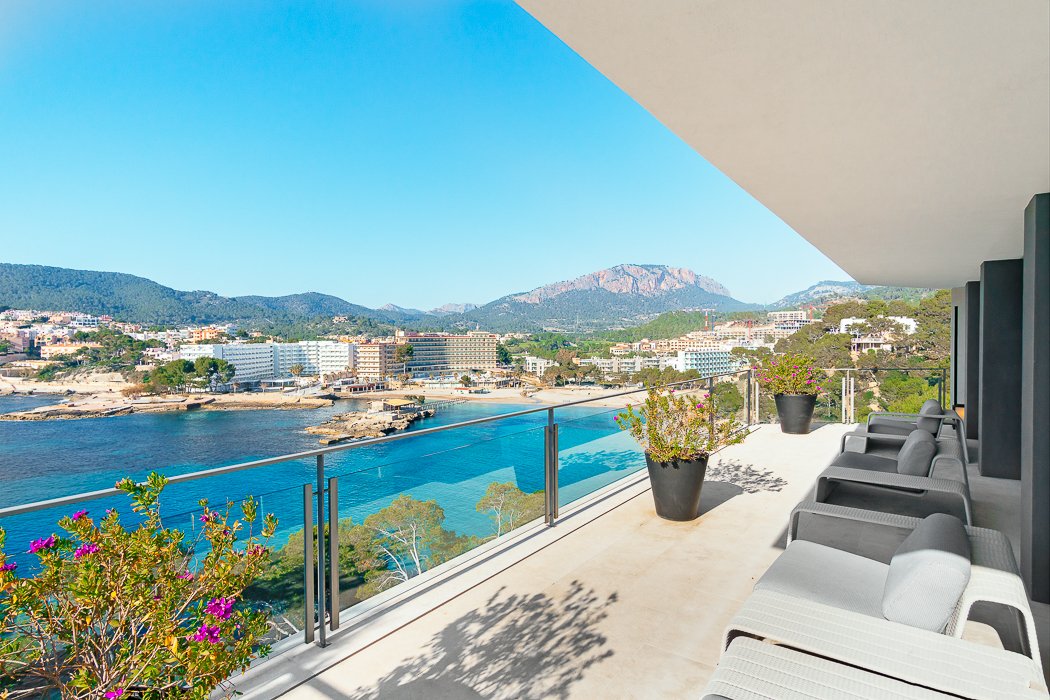 Spacious balcony in a seafront luxury villa in Camp de Mar, Mallorca, offering panoramic views of the Mediterranean Sea. The elegant design features modern outdoor seating, creating a perfect space for relaxation or al fresco dining while enjoying the tranquil coastal surroundings and breathtaking sunsets.