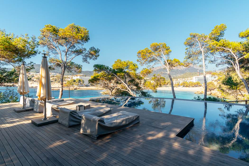 Exquisite pool and deck area at a seafront luxury villa in Camp de Mar, Mallorca, featuring a stunning infinity pool that blends seamlessly with the sparkling Mediterranean Sea. The spacious deck is equipped with stylish loungers, creating an elegant space for sunbathing, relaxation, and enjoying the serene coastal surroundings.