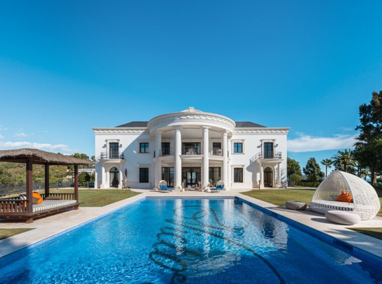 Stunning facade of a luxury villa in Las Chapas, Marbella, showcasing elegant architectural design with clean lines, large windows, and a harmonious blend of modern and classic elements. Surrounded by lush greenery, the villa exudes timeless elegance and exclusivity, offering a perfect balance of sophistication and natural beauty.