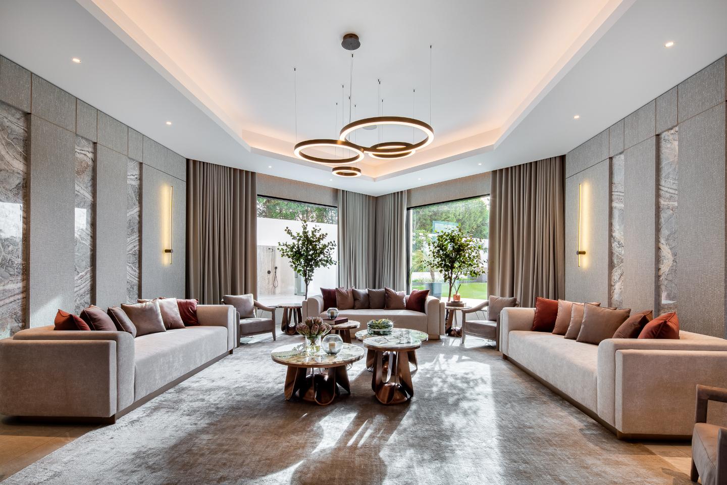 Luxurious living room in an ultra-luxury mansion in Emirates Hills, featuring contemporary furnishings, floor-to-ceiling windows with stunning skyline views, and a sophisticated neutral color palette. The space exudes elegance with modern decor and ambient lighting.